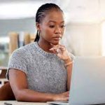 image of a black girl in front of her laptop while thinking